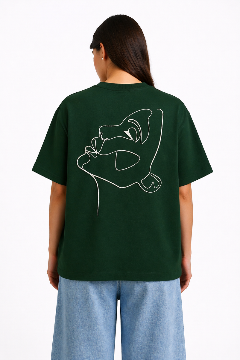 Femme portant un t-shirt oversize vert foncé Rich.Art avec illustration minimaliste d’un visage abstrait blanc imprimée au dos