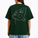 Femme portant un t-shirt oversize vert foncé Rich.Art avec illustration minimaliste d’un visage abstrait blanc imprimée au dos